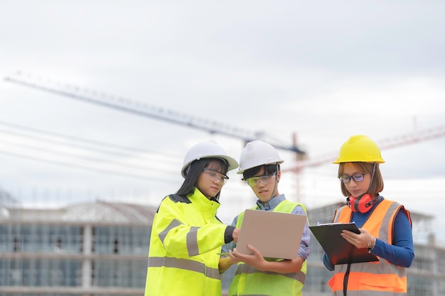 Des ingénieurs jeunes et seniors discutent des travaux d'un grand bâtiment en constructionTrois personnes travaillant sur le site en construction