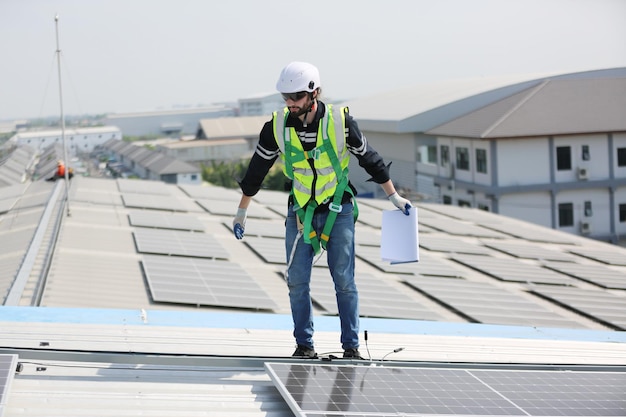 Ingénieurs masculins matures marchant le long des rangées de panneaux photovoltaïques sur le toit d'une centrale solaire