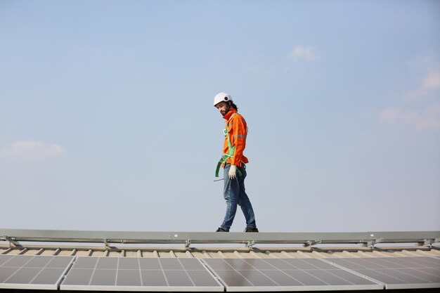 Ingénieurs masculins matures marchant le long des rangées de panneaux photovoltaïques sur le toit d'une centrale solaire