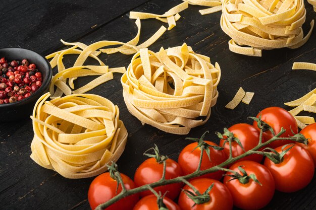 Ingrédient de la cuisine méditerranéenne traditionnelle pâtes crues tagliatelles sur fond de table en bois noir