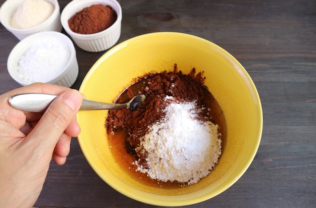 Ingrédient de mélange à la main dans un bol pour la cuisson du gâteau au chocolat