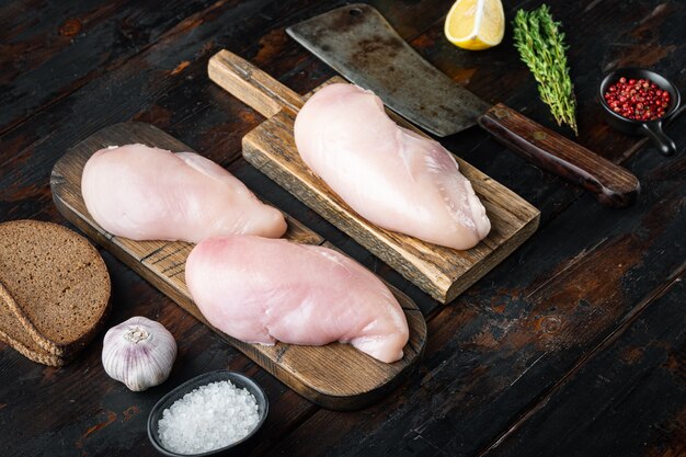 Ingrédient de poitrines de poulet non cuites émiettées avec couteau de boucher, sur une table en bois foncé