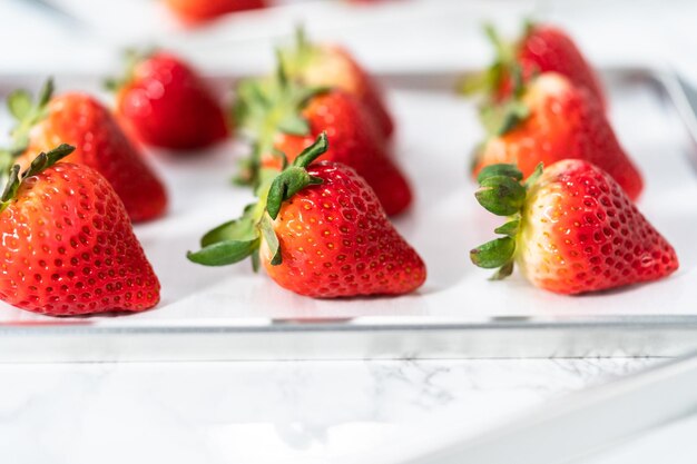 Ingrédient pour faire des fraises enrobées de chocolat avec des fraises biologiques.