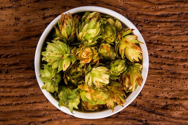 Ingrédients de brassage de bière Cônes de houblon dans un bol blanc sur fond de bois. Concept de brasserie de bière.