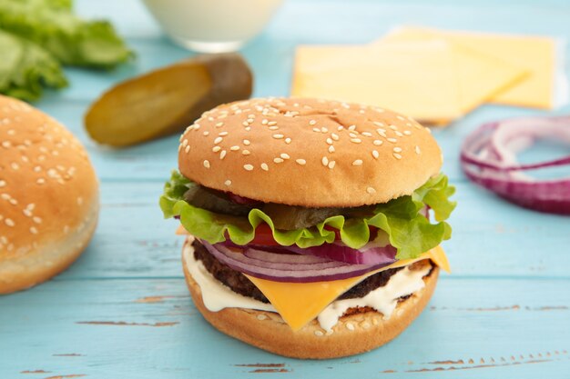 Ingrédients burger maison disposés sur une surface en bois bleue