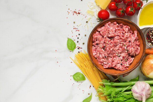 Ingrédients crus pour la cuisson des pâtes bolognaises sur une table en marbre blanc. concept de cuisine. vue de dessus