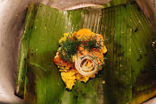 Photo ingrédients crus d'un tamale colombien sur une feuille de banane sur une table en bois dans la cuisine