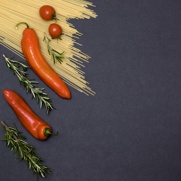 Ingrédients de la cuisine italienne. Nature morte de la cuisson des pâtes sur une vue de dessus de fond noir. Cuillères en bois avec des épices. Cadre de produits et légumes.