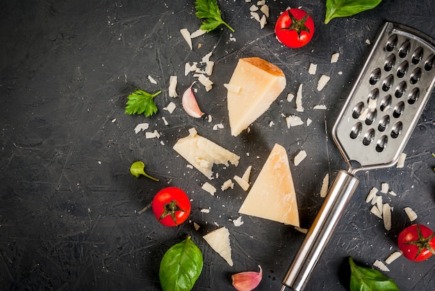 Ingrédients de la cuisine italienne.Parman râpé et un morceau, avec une râpe, des feuilles de basilic, de l'ail et des tomates cerises