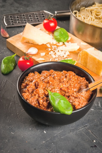 Ingrédients de la cuisine italienne. Produits pour la préparation de pâtes bolognaises, le processus de cuisson. Spaghetti soudé dans une poêle, sauce bolognaise, basilic, ail, tomate, parmesan