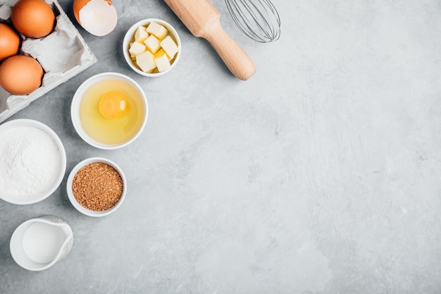 Ingrédients de cuisson farine oeufs sucre beurre rouleau à pâtisserie et fouetter sur la table de la cuisine vue de dessus espace de copie