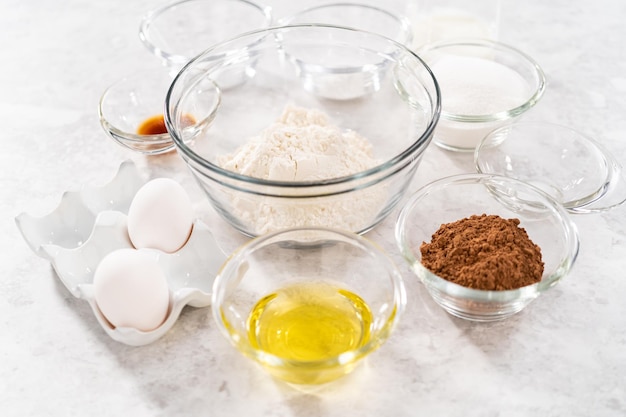 Ingrédients dans des bols à mélanger en verre pour cuire des cupcakes au chocolat et aux fraises