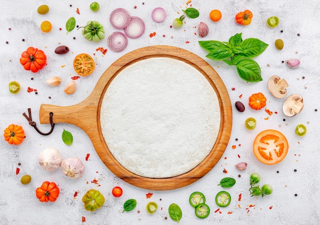 Les ingrédients de la pizza maison mis en place sur fond de béton blanc