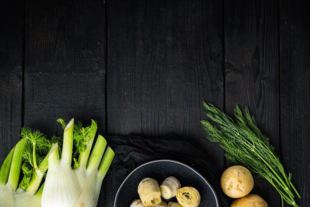 Ingrédients de pommes de terre et d'artichaut al forno, sur table en bois noir, vue de dessus avec espace pour le texte