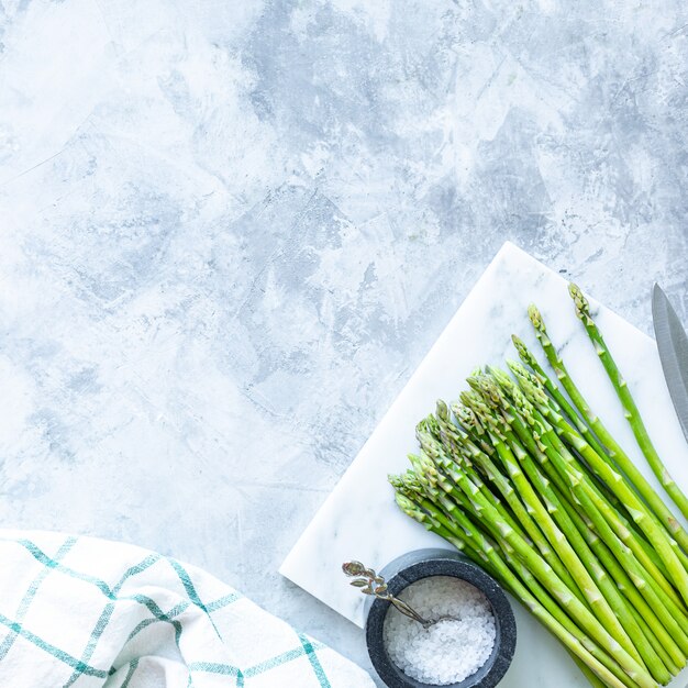 Ingrédients pour cuisiner sur un fond de béton gris. Un tas d'asperges vertes fraîches. Vue de dessus. Espace copie