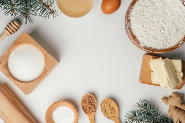 Ingrédients pour la cuisson des biscuits de pain d'épice de Noël dans des bols en bois sur une table blanche. Espace de copie. Vue de dessus