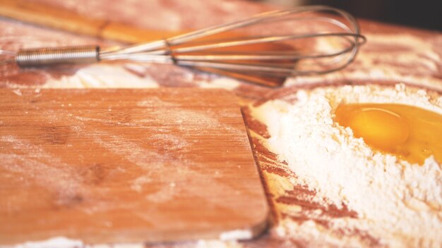 Ingrédients pour la cuisson du pain fait maison. Oeufs, farine. Fond en bois, vue latérale. Flou et lumière