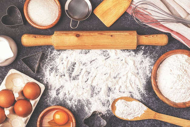 Ingrédients pour la cuisson de la farine cuillère en bois rouleau à pâtisserie oeufs vue de dessus espace de copie