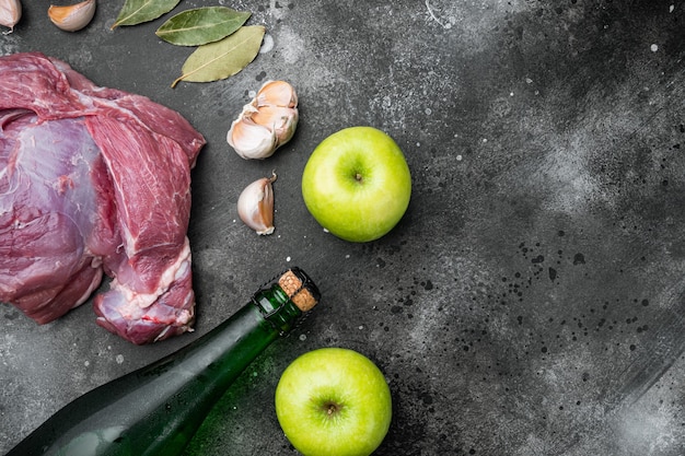 Ingrédients pour l'ensemble de longe de porc rôti, avec du cidre sec de pomme, sur fond de table en pierre noire noire, vue de dessus à plat, avec espace de copie pour le texte