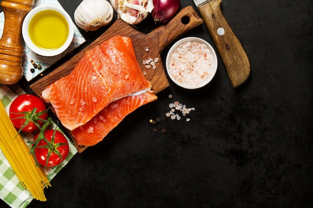 Ingrédients pour la fabrication de pâtes et de filets de saumon sur une planche de bois