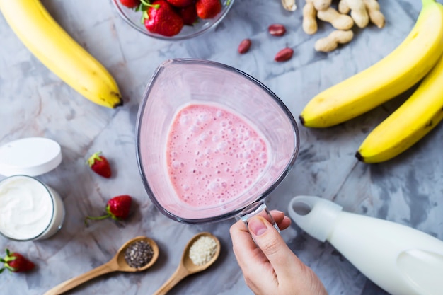 Ingrédients pour faire des smoothies fraise banane sur une table grise