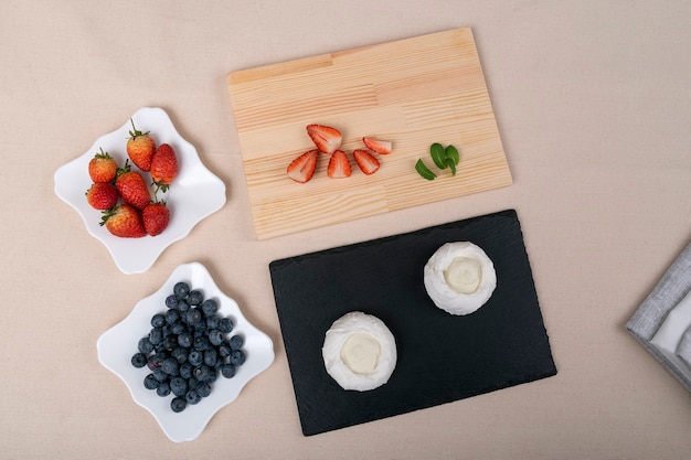 Ingrédients pour le gâteau Pavlova : fraises, myrtilles et meringue. Vue de dessus.