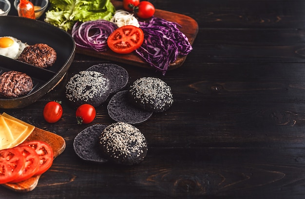 Ingrédients pour un hamburger noir sur une surface en bois