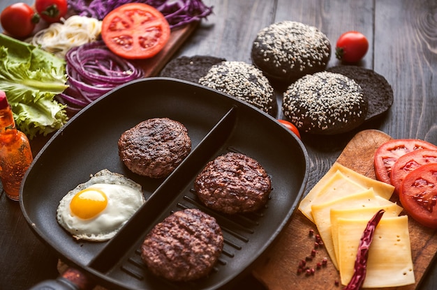 Ingrédients pour un hamburger noir sur une surface en bois