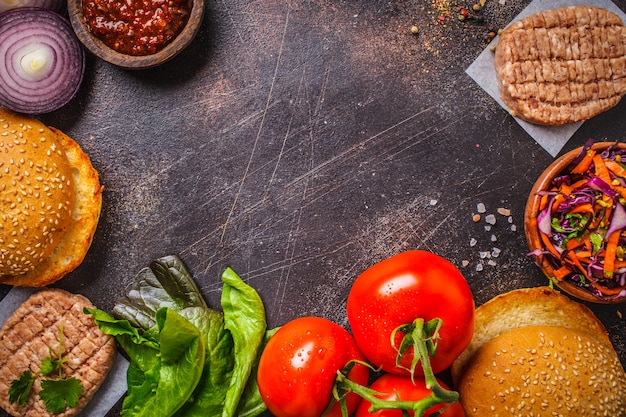 Ingrédients pour hamburgers à la viande sur fond sombre, vue de dessus, espace copie.