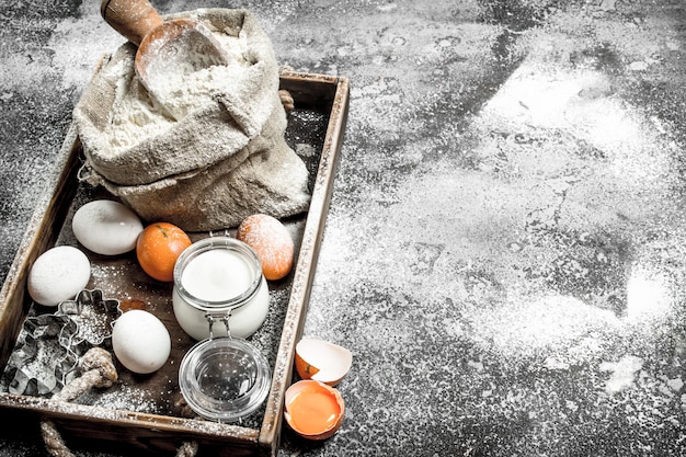 Ingrédients pour la pâte dans un plateau en bois sur table rustique.