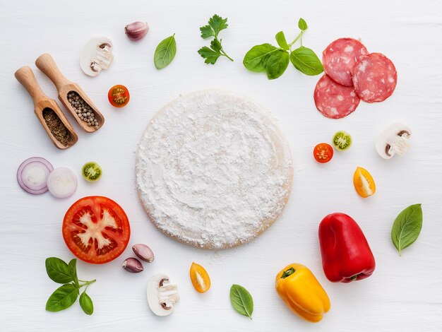 Les ingrédients pour une pizza faite maison sur un fond de bois blanc