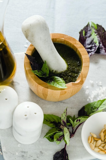 Ingrédients pour la préparation du pesto violet au basilic italien avec du fromage sur une nappe bleue en lin