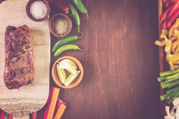 Ingrédients pour préparer des fajitas au steak sur une table en bois.