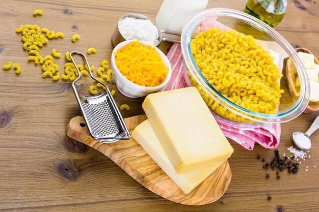 Ingrédients pour préparer des macaronis au fromage sur une table en bois.