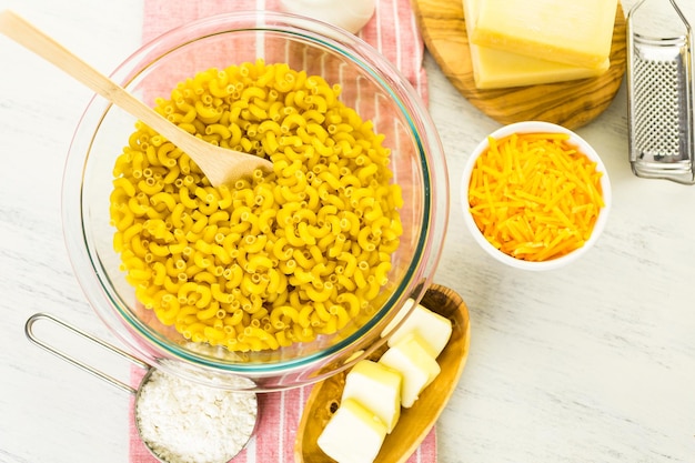 Ingrédients pour préparer des macaronis au fromage sur une table en bois.