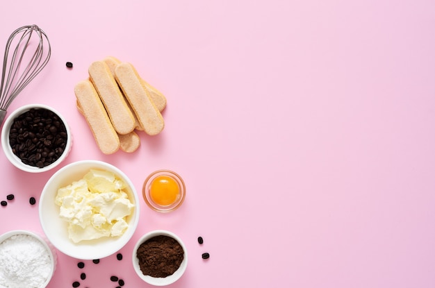 Ingrédients pour préparer le tiramisu sur fond rose. Processus de cuisson. Dessert italien classique.