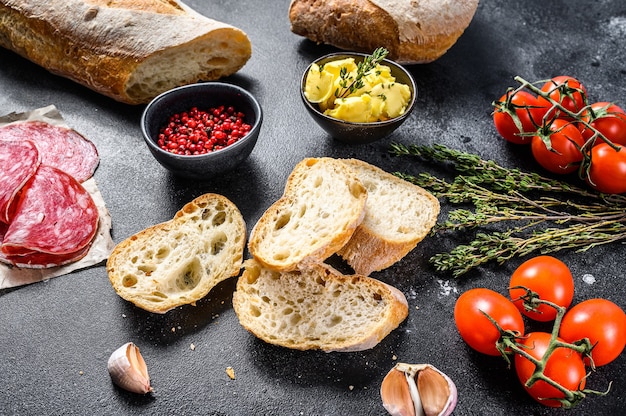 Ingrédients pour sandwich au beurre, viande fumée, baguette, tomates cerises, parmesan, ail et épices