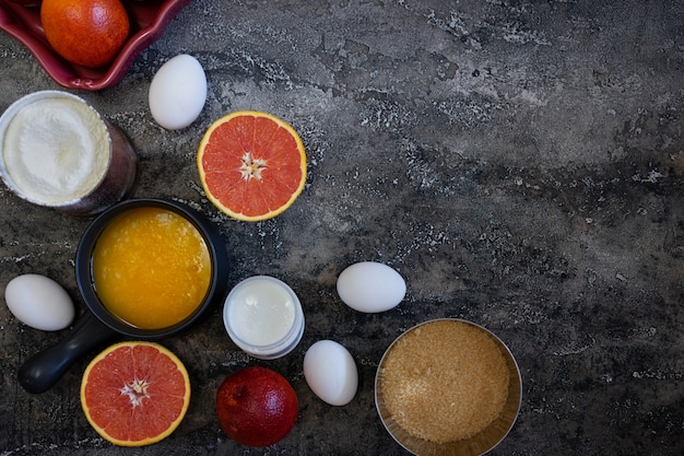 Ingrédients pour soutenir un gâteau à l&#39;orange sanguine sur fond sombre