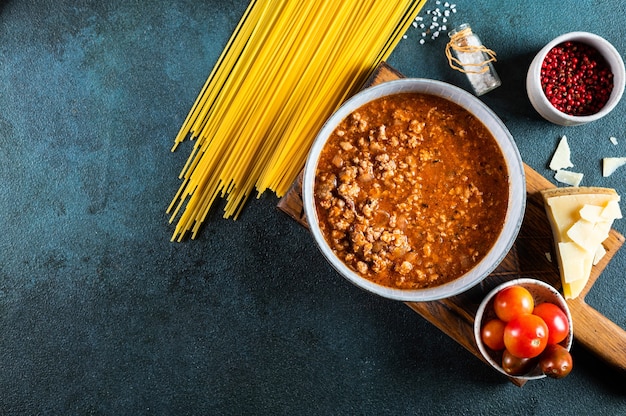 Ingrédients pour spaghetti bolognaise sur fond sombre. Pâtes bolognaises crues. Plat de pâtes. bolognaise italienne. Ingrédients alimentaires. Vue de dessus de pâtes