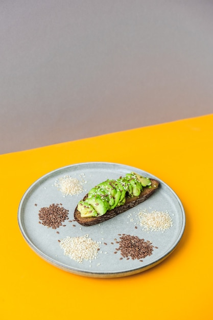 Ingrédients pour un toast à l'avocat sain. Graines de lin de sésame. Régime céto végétalien. Alimentation équilibrée. Guacamole végétarien à la mode. Concept minimaliste dans un style isométrique dans des couleurs tendance.