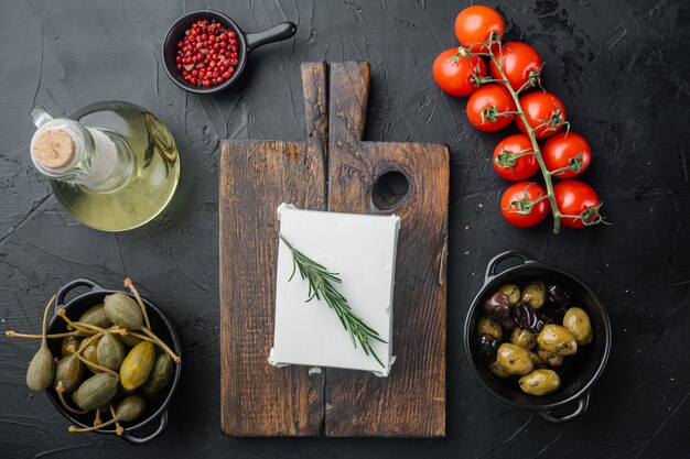 Ingrédients principaux de la salade grecque, mélange d'olives fraîches, fromage feta, tomates, sur table noire, mise à plat