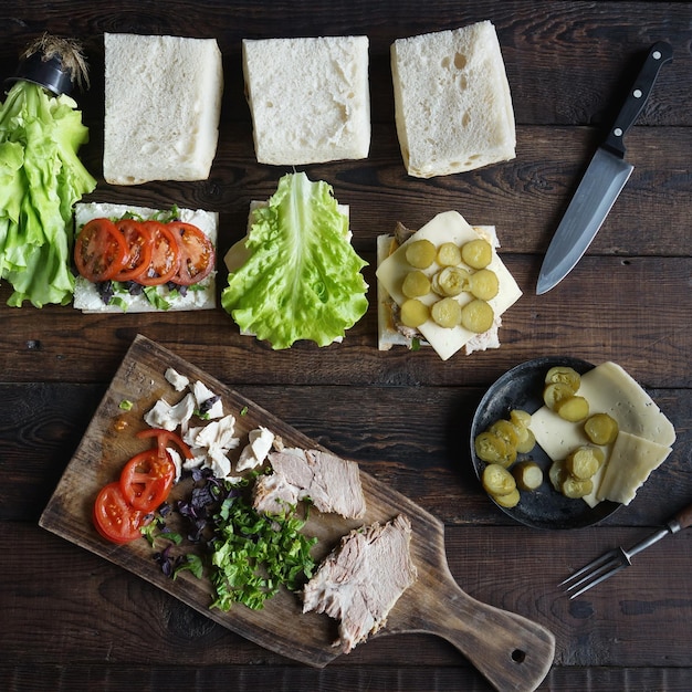 Ingrédients de sandwichs sur une planche de bois sur fond sombre