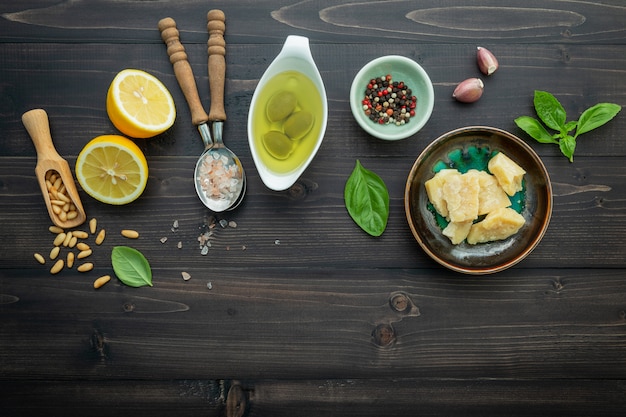 Les ingrédients de la sauce pesto verte sur un fond en bois foncé.