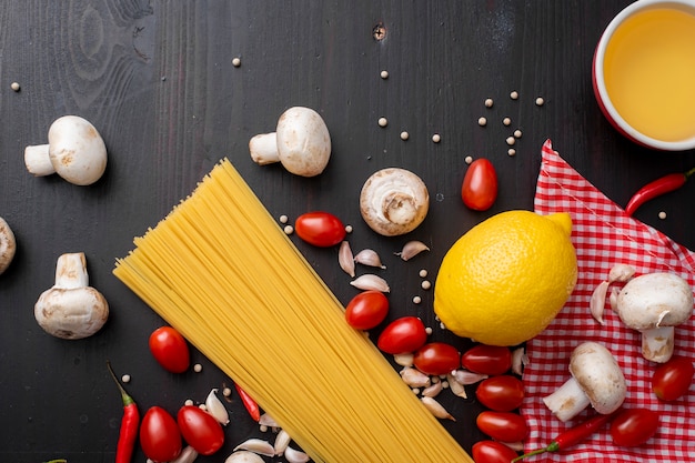 Ingrédients de spaghettis sur un bureau en bois noir, vue de dessus.