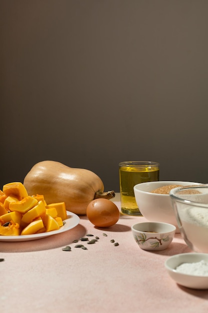 Ingrédients de la tarte à la citrouille dans des bols sur une table rose