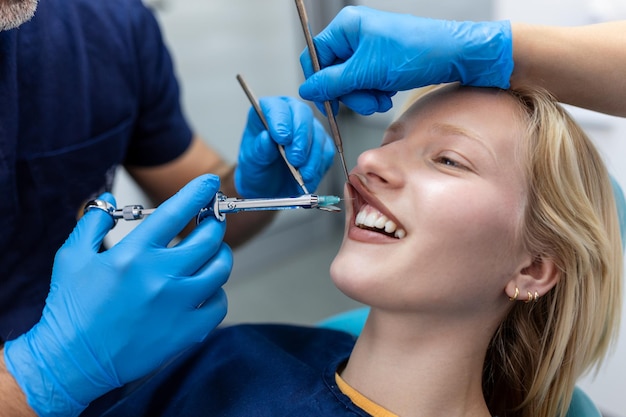 Injection d'anesthésie anti-douleur Dentiste examinant les dents d'un patient dans un cabinet de dentisterie moderne Photo recadrée en gros plan avec fond Médecin en masque facial médical jetable