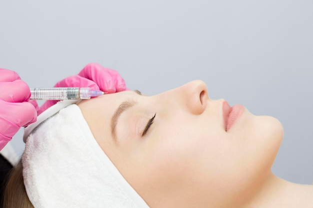 Injection dans le front au salon spa Les mains du médecin Biorevitalisation Soin du visage d'un cosmétologue