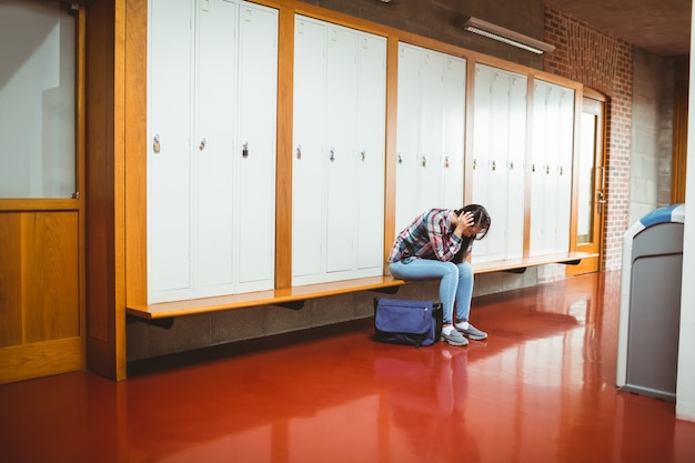 Inquiet étudiant assis avec les mains sur la tête