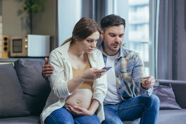 Inquiétude Jeune famille femme enceinte et mari détenant une carte de crédit et un téléphone Vérifier ne pas comprendre Appeler la banque