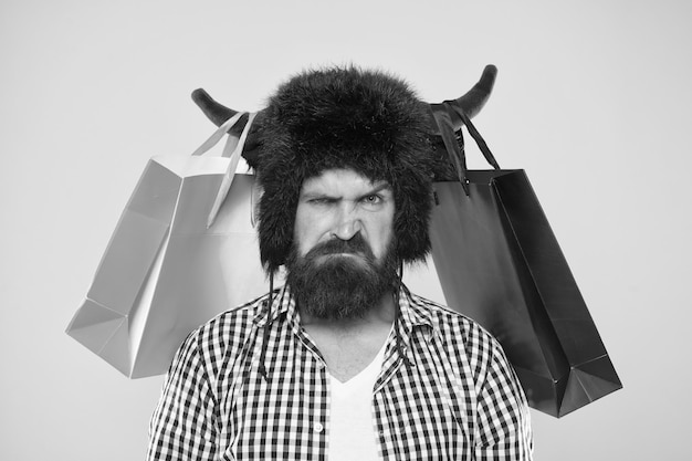 Insatisfait de l'achat Hipster mécontent de son achat dans des sacs en papier suspendus à des cornes de taureau Homme barbu brutal avec achat personnel Achat d'achat de mode